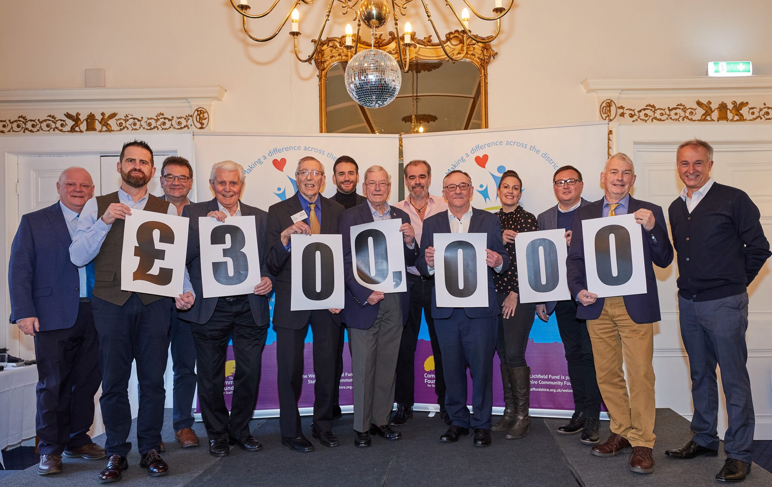 A group holding cards spelling out £300,000 at a We Love Lichfield celebration.