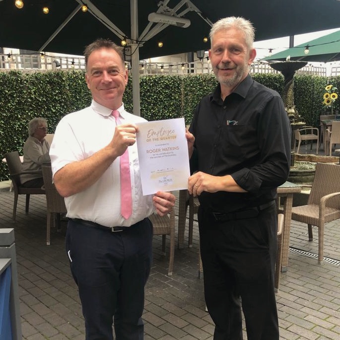 Two people holding an Employee of the Quarter certificate.